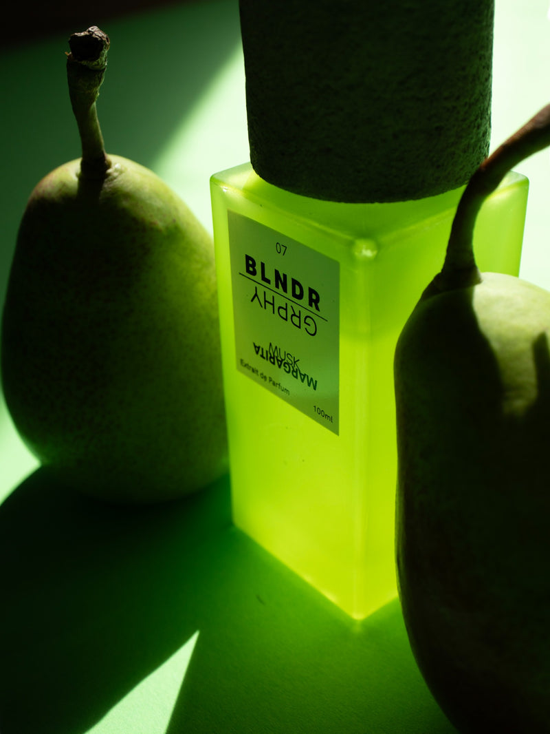 Musk Margarita extrait de parfum bottle glowing green among pears